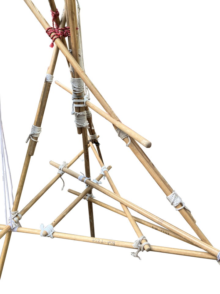 Bottom of Troop 201's flagpole: a tripod, a center pole, and its reinforcements. Each tripod leg is around 7ft and is made of two sticks. Three sticks connect each tripod leg and the center pole's reinforcements.