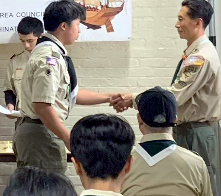 Scout shakes scoutmaster's hand