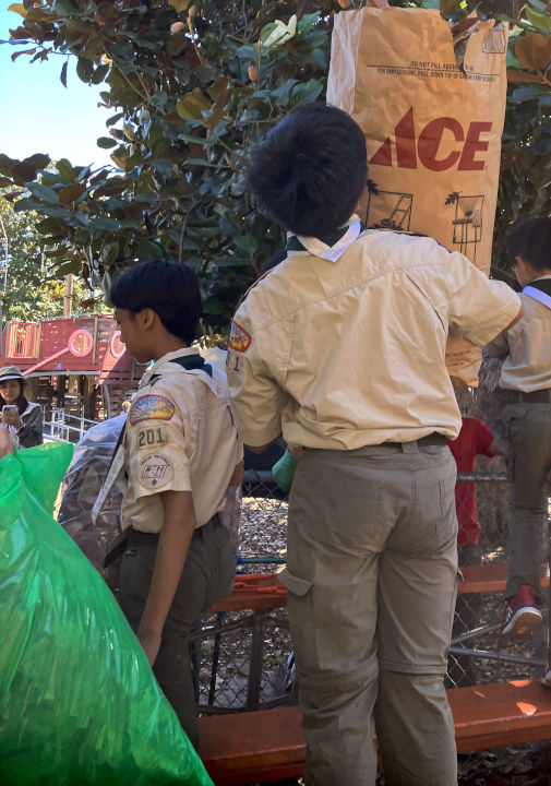 Worker lifts bag of leaves over a fence