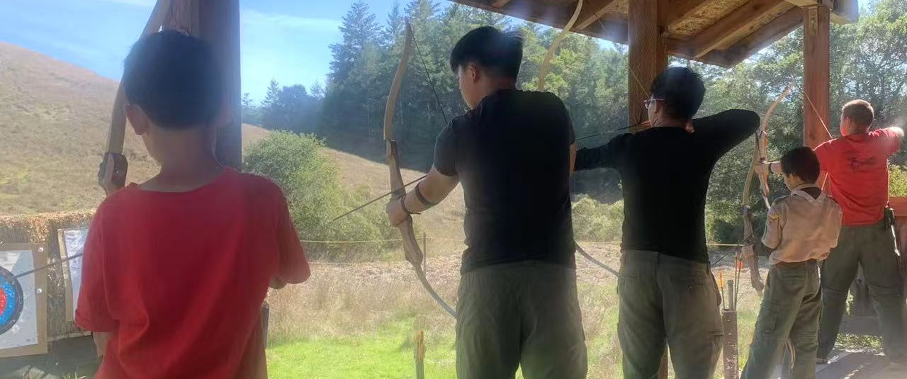 Five people in a line holding bows