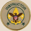 Instructor badge: A golden trefoil with stars on outer edges, an eagle holding a shield on top of the trefoil, a circle encompassing the trefoil, two stars below the trefoil, and the word instructor curved near the top of the badge